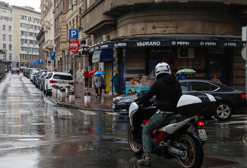 Čovek vozi motor po kiši